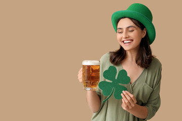 Beautiful young woman in leprechaun hat with glass of beer and clover on brown background. St....
