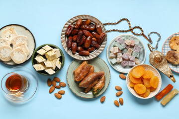Composition with different Eastern sweets, tasbih and Aladdin lamp for Ramadan on color background