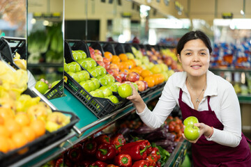 Asian female seller in apron takes crisp apples from window.Concept of proper nutrition,healthy lifestyle