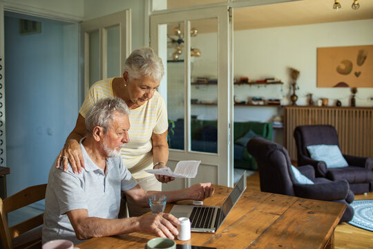 Senior couple managing finances online with laptop at home