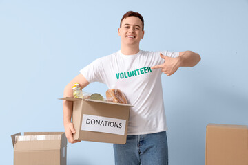 Male volunteer with food donations near blue wall