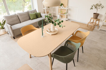 Interior of light room with dining table, sofa and plants