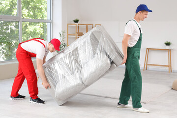 Loaders carrying sofa in stylish room