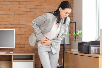 Young businesswoman suffering from severe abdominal pain in office