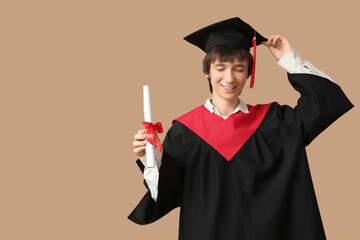 Male graduating student with  diploma on beige background