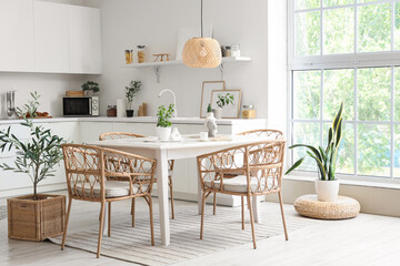 Interior of light dining room with table and wicker chairs