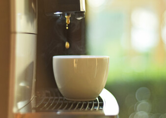Turquoise cup pouring with two jets of hot coffee from beige espresso coffee machine pump. Close-up of coffeemaker. Coffee latte preparation.