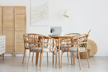 Table and wicker chairs near white wall in dining room