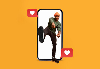 A person playfully poses in front of a bright orange background, emerging from a smartphone. Heart icons indicate active social media engagement, conveying joy and love.