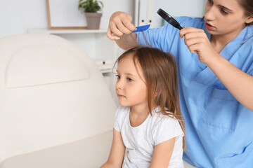 Female doctor with magnifier combing little girl's hair with pediculosis in clinic