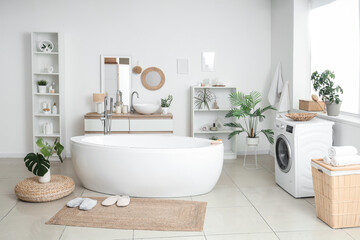 Interior of bathroom with bathtub, washing machine and wicker mat