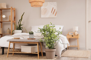 Interior of stylish bedroom with cozy bed and grey bedside bench