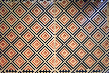 Geometric Patterned Wall in Orange, Beige, & Black Diamond Motifs, Symmetrical, Modern Style, Repeating Design, Close-Up Detail Shot, Intricate Design