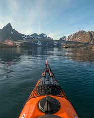 A red sea kayak on mirror flat water surrounded by mountains.