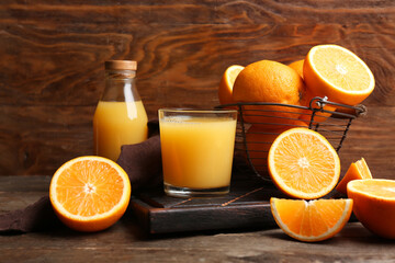 Oranges with glass and bottle of tasty juice on wooden background