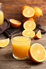 Half of fresh orange with glass of tasty juice on wooden background