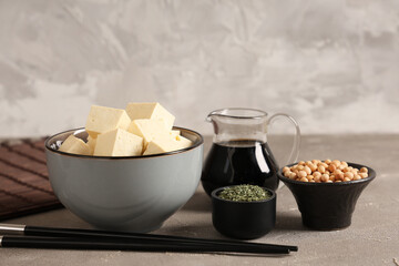 Bowl with tasty tofu cheese on grey grunge background