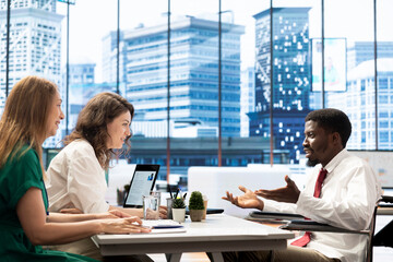 Professional in wheelchair collaborating with colleagues in office, working together, highlighting...