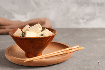 Bowl with tasty tofu cheese on grey grunge background