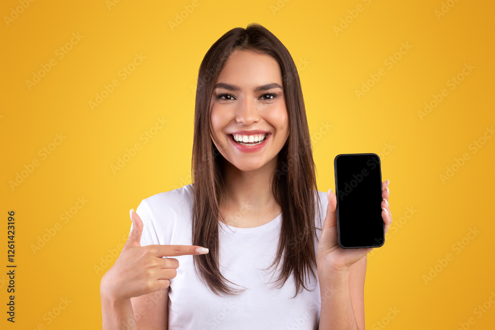 Poster use this cool app. cheerful young lady holding smartphone with black empty screen, pointing at blank