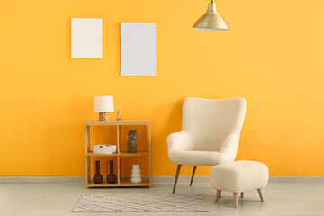 Armchair and shelving unit with empty posters on yellow wall