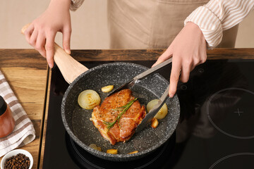 Woman frying tasty steak in kitchen
