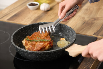 Woman frying tasty steak in kitchen