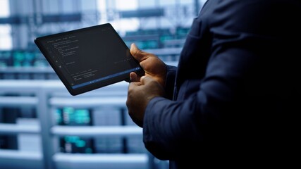 Engineer in high tech facility using tablet to patch network issues leading to slow data transfer...