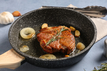 Frying pan with roasted steak on blue background