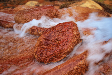 Rusty Red Stone Against a Mineral Spring Flow