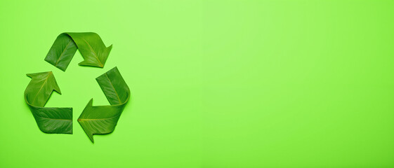 Obraz premium Recycling symbol made of green leaves on a vibrant green background representing sustainability and environmental awareness