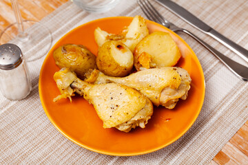Two appetizing roasted chicken legs served with crispy skinned baked potatoes. Tasty homemade dinner..