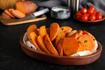 Bowl with baked sweet potato on black grunge background