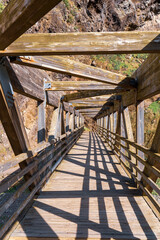 Fototapeta premium A wooden bridge extending into the distance with a natural rocky surrounding.