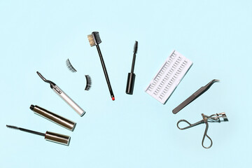 Different false eyelashes with tools and mascara on blue background