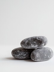 Three smooth gray stones stacked on a white background.