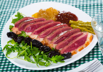 Tasty roasted duck breast Magret with prunes, herbs and sauces on plate