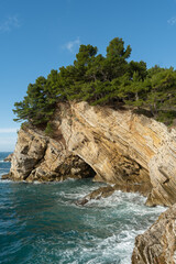 Mediterranean rocky cliff with pine trees overlooking the sea and a coastal grotto