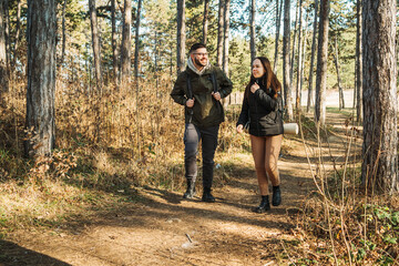 Fototapeta premium Young caucasian couple boyfriend and girlfriend hiking or trekking through the forest