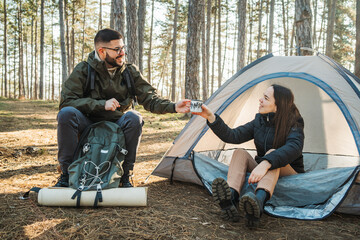 Young caucasian couple boyfriend and girlfriend camping in the forest