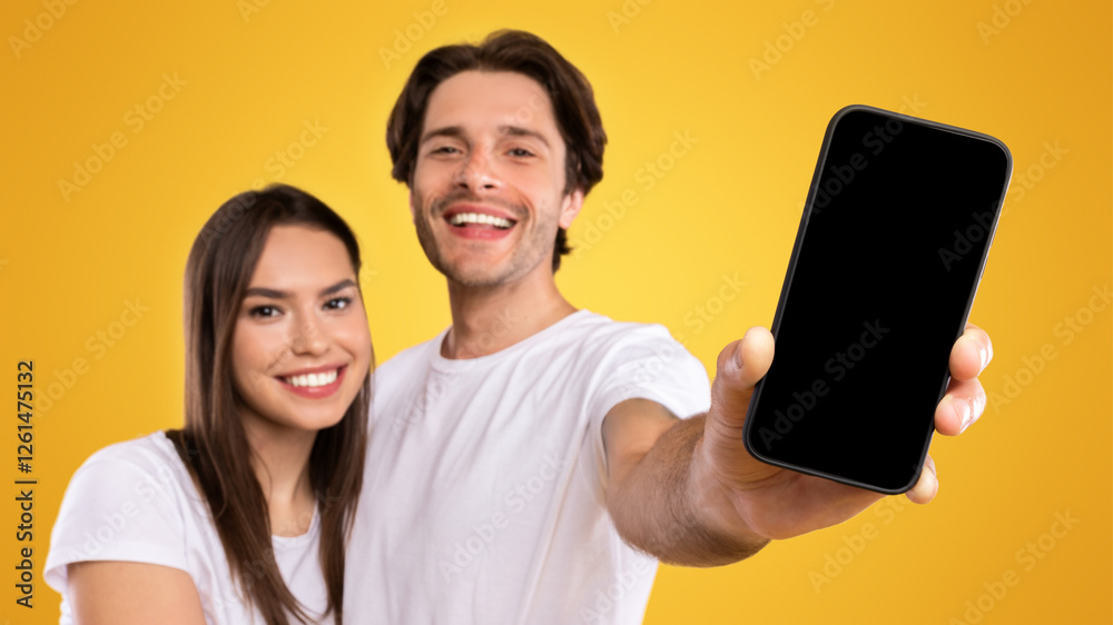 Poster handsome guy holding and showing smart phone with black empty screen in hand close up to camera, moc