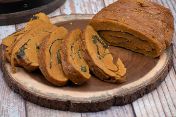 Vegan seitan spinach stuffed meat roll, sliced, in wooden board