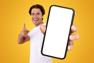 Mobile App Advertisement. Handsome Excited Man Showing Pointing At White Empty Smartphone Screen...