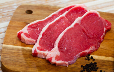 close up of pieces of striploin on wooden table