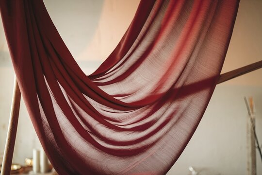 Luxurious deep burgundy sheer fabric texture close-up. Elegant wine-colored draped silk or chiffon textile flowing as a soft background or spa and interior design backdrop.