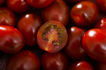 Closeup of whole and sliced mini tomatoes of exotic selection variety of Kumato. Natural food background