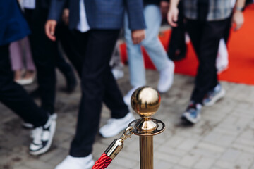 Naklejka premium Red carpet with ropes and golden barriers on a luxury party entrance, cinema premiere tv film festival event award gala ceremony, wealthy rich guests arriving, outdoor decoration elements, summer day