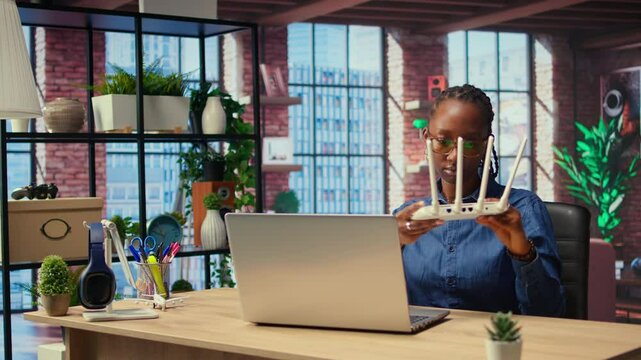 African American woman rebooting the wi fi modem by pulling out cables, checking with the internet provider for support. Troubleshooting ongoing Wi Fi connectivity issues. Camera A.