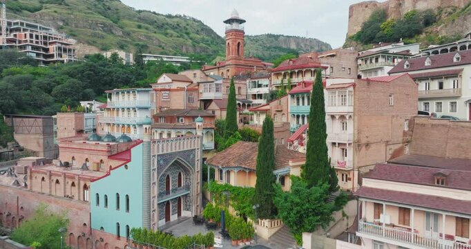 Tbilisi, Georgia, Abanotubani Baths, historical building with red tower, Narikala Castle, old city, traditional balconied houses, tile decorations, cultural heritage.