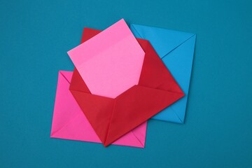 The red envelope contains empty pink sticky notes on top of a pile of blue and pink envelopes on a...